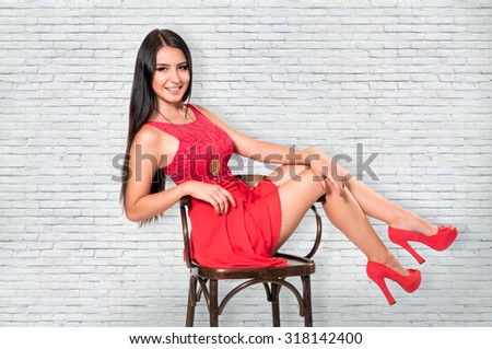 Young gorgeous caucasian brunette sitting and posing on a chair