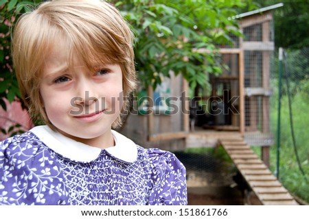 This young girl gives a far-away look and sorrowful expression while standing in a turkey pen.