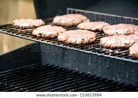 Hamburgers are almost done cooking on a backyard grill.