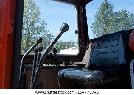 This interior view of a heavy equipment cabin shows the various levers used to control the equipment.