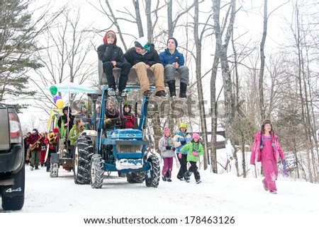 Calais, Vermont, USA - February 15, 2014:  Kids in colorful snow gear march alongside the float in Maple Corner\'s annual Mardi Gras parade.