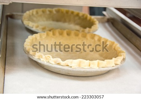 Two pie crusts sit on a rack in a commercial kitchen.