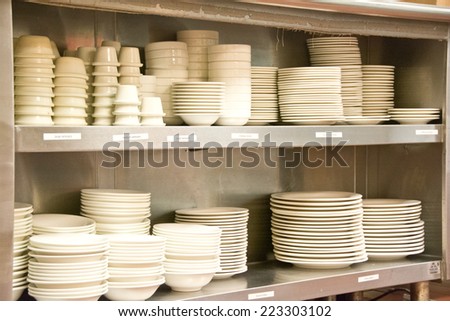 Dishes are stacked on metal shelves in a commercial kitchen.