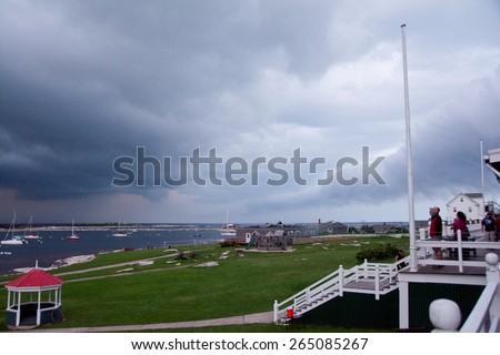 Rye, NH, USA - August 7, 2014: Visitors to Star Island watch a passing summer storm from the porch of the Oceanic Hotel.