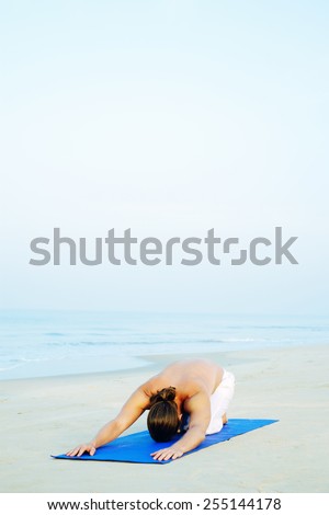 Long Hair Athletic Man with No Shirt doing Yoga on Blue Mat at the Beach\
Child pose - Balasana