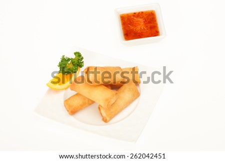 Fried spring rolls on a white plate with spicy sauce and lemon slice studio shot on white background