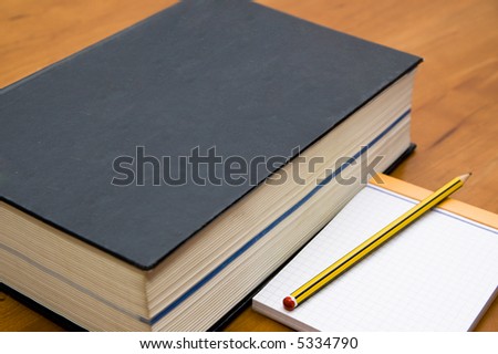 Big dictionary, notepad and pen on a wood table