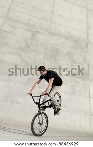 Young BMX bicycle rider on a grey urban concrete background