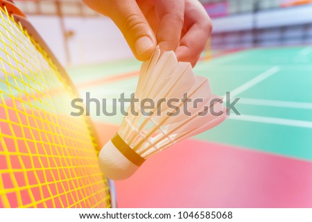 close up hand hold serve badminton shuttlecock with blur badminton court background