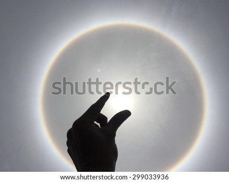 sun halo phenomenon with hand silhouette