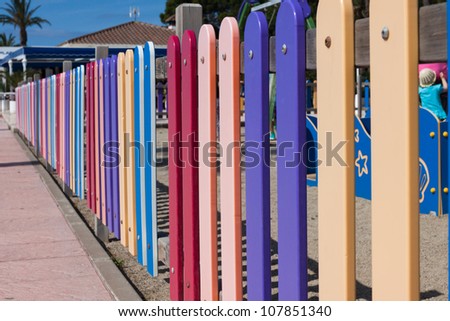 Many colourful rows of painted wood on a playground fence