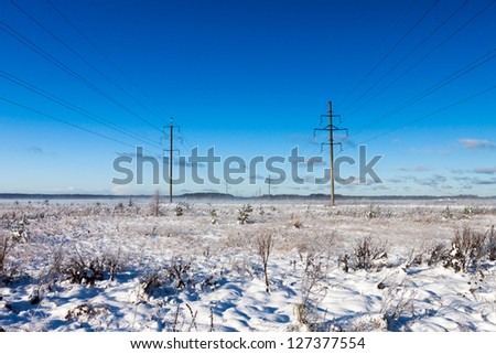 Power lines in winter snow field on a background of the blue sky