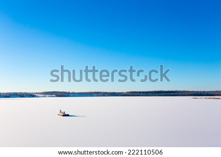 Frozen lake with ice and snow, sunny winter day. Forest