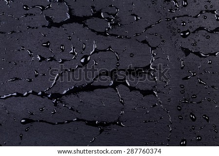 Water drops on dark stone surface of basalt or granite