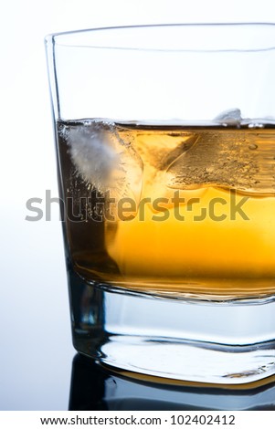 glass of whiskey with ice cubes on white background