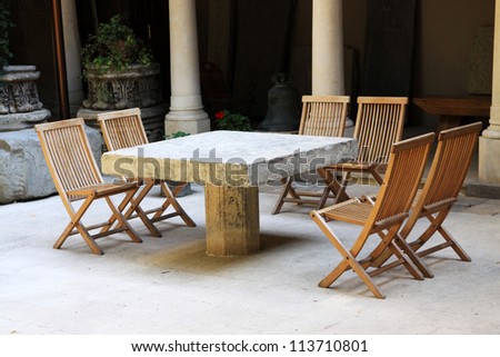 Stone table and wooden chairs in a courtyard from Bucharest in a summer day.