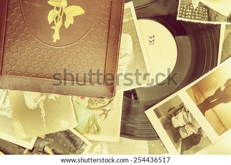 Old photo-album with retro pictures and black vinyl record on the table.