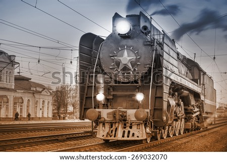 Retro steam train stands on the station at evening time. Vintage image.