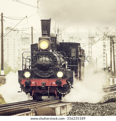 Moscow, Russia - September 3, 2015: Old retro russian steam locomotive of Ov series moves under the pouring rain. Locomotives of Ov series were made from 1890 to 1915 years.