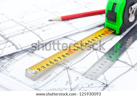 Measurement tools and a pencil on top of architectural drawings in perspective.