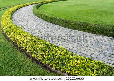 The Stone block walk path in the park with green grass background The Stone block walk path in the park with green grass background