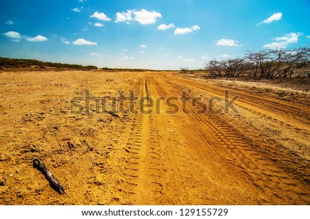 A well used dirt road running though a desolate dry desert.