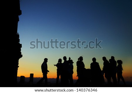 Silhouettes of a group of people on the roof the cathedral in Mexico City with skyscrapers in the background at sunset