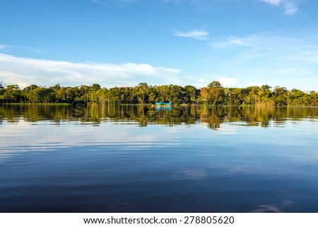 Jungle sky and boat reflected in the clear blue water of the Javari River in the Brazilian Amazon Rainforest Jungle sky and boat reflected in the clear blue water of the Javari River in the Brazilian Amazon Rainforest