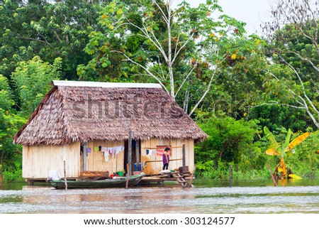 IQUITOS, PERU - MARCH 11:  Woman standing on the porch of her house surrounded by water near Iquitos, Peru on March 11, 2015