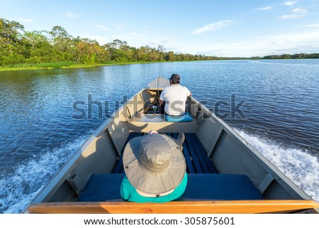 IQUITOS, PERU - MARCH 13: Tourist and guide ride in a boat in the Amazon rain forest near Iquitos, Peru on March 13, 2015