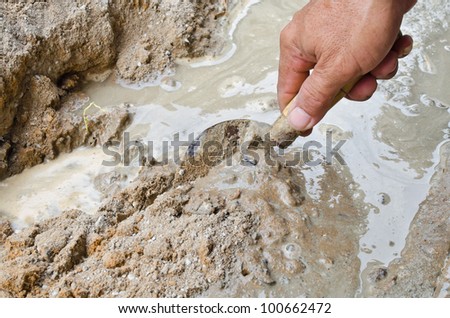 Closeup mason hand spreading fresh concrete mix with trowel