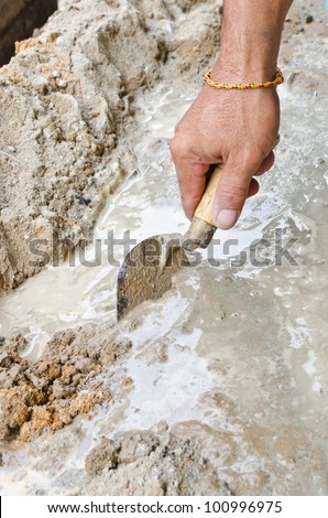 Closeup mason hand spreading fresh concrete mix with trowel