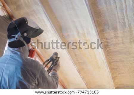 Polyurea Spraying, warming foam coating of roof, worker during insulation process, selective focus on wall