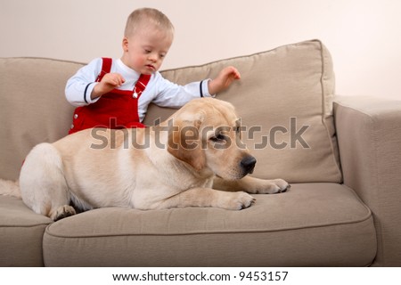 A dog and young boy with Down Syndrome together on a sofa.