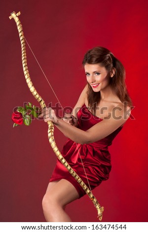 Young woman with bow and red rose as arrow on red background.  Concept for Valentine\'s day.