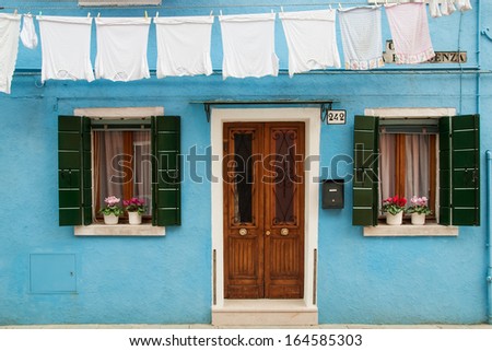 The facade of blue house with windows, door and washing on the island of Burano (Venice, Veneto, Italy).