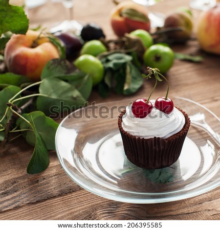 Cupcake with whipped cream and cherries on decorated wooden table, shallow DOF.