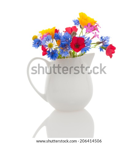 Small white milk jug with wildflowers isolated on white background.