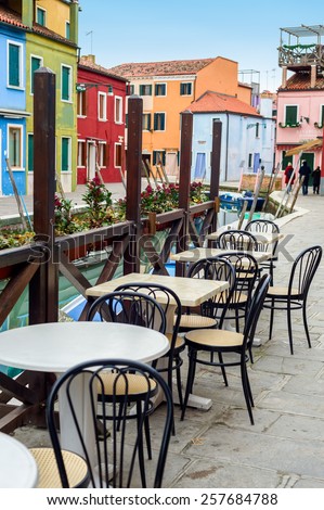 Street view of a cafe terrace with empty tables and chair on the famous island Burano, Venice, Italy.