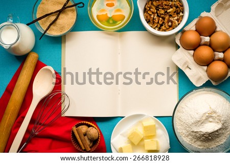 Baking cake in rural kitchen - dough recipe ingredients (eggs, flour, milk, butter, sugar) with walnuts, vanilla. Recipe book in the center.