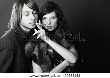 Stylish couple smoking a cigar on black background - black and white