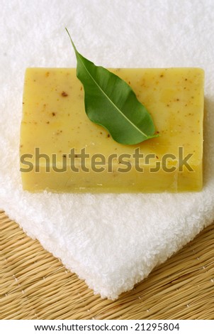 Aromatic soap with green leaf on white folded towel
