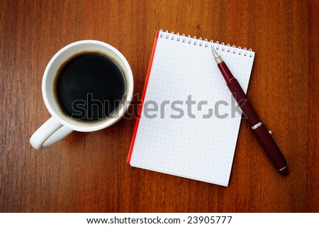 Pencil on a white spiral squared notebook with cup of coffee viewed from above