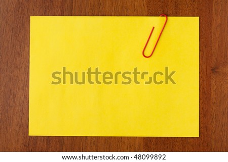 Blank yellow note with red clip on wooden background. Just add your text