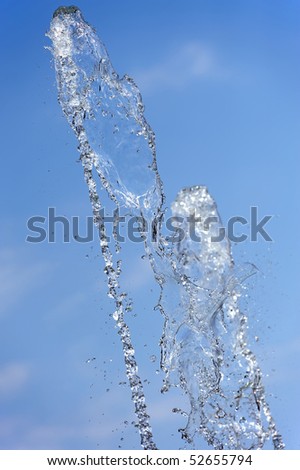 Water shooting out of a fountain with a bright blue background
