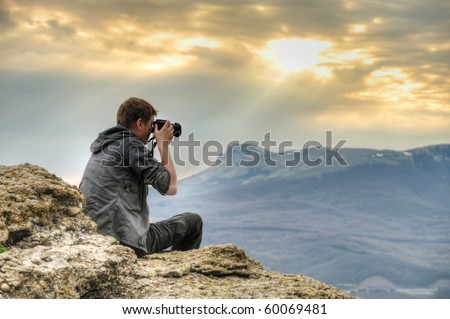Nature photographer with digital camera on top of the mountain. HDR.