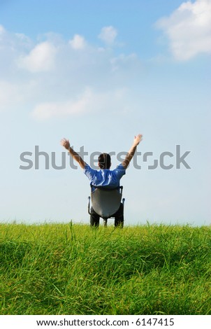 a manager is sitting on a chair in nature on a green meadow an blue sky with clouds