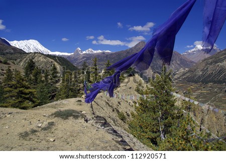A string of blue prayer flags strung against an azure blue sky, near Manang on the Annapurna Circuit. Prayer flags promote peace, compassion, strength, and wisdom in Tibetan Buddhism.
