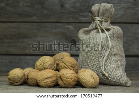 Walnuts in burlap bag on wooden background