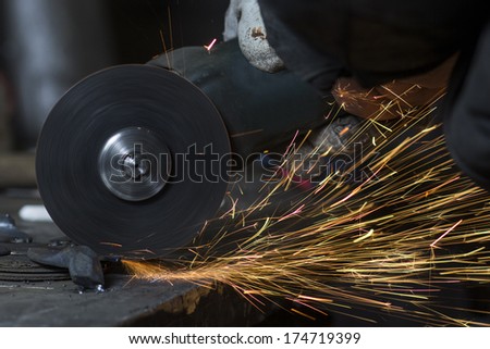Electric wheel grinding on steel structure by worker in factory